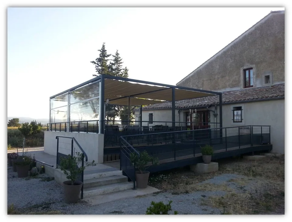 Pergola de restaurant avec toiles coulissantes tendues et stores pare-vent transparents