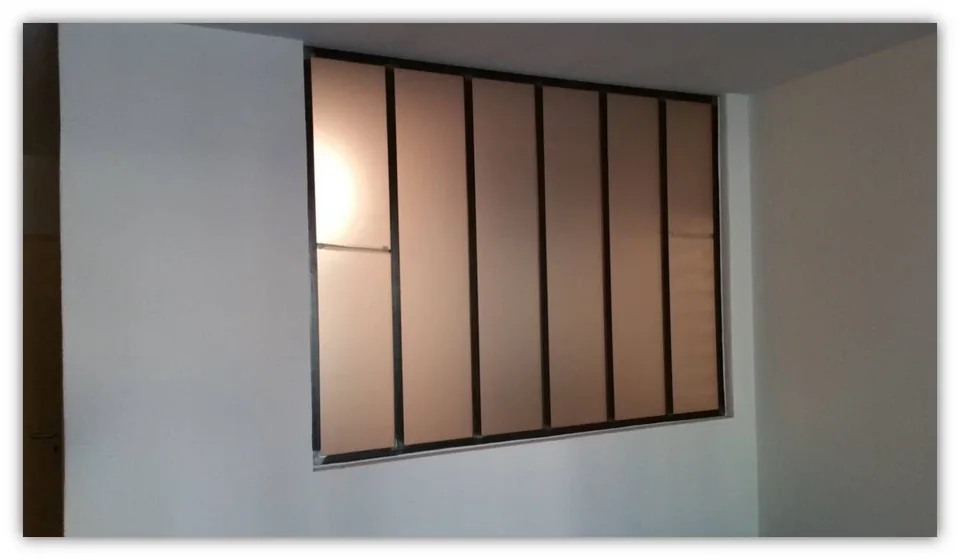 Verrière de séparation dans un petit appartement permettant ainsi de donner de la lumière tout en préservant l'intimité grâce au verre satiné